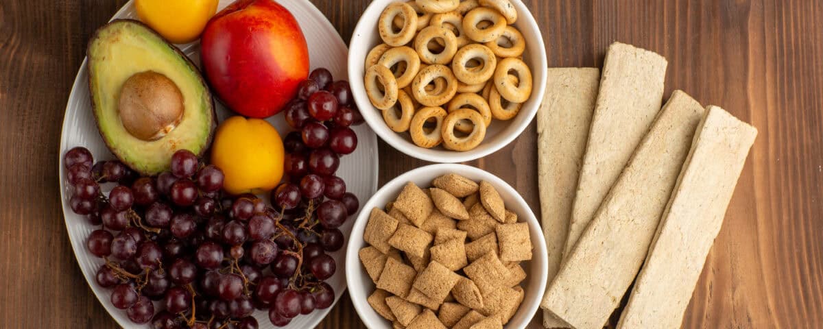A guide to healthy, satisfying options: grapes, avocado, nectarines, cereal bowls, and breadsticks on a wooden table. | Emping SG