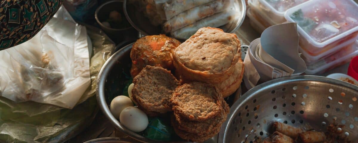 A culinary journey of Vietnamese snacks: spring rolls, fried treats, and eggs displayed in metal bowls and containers. | Emping SG