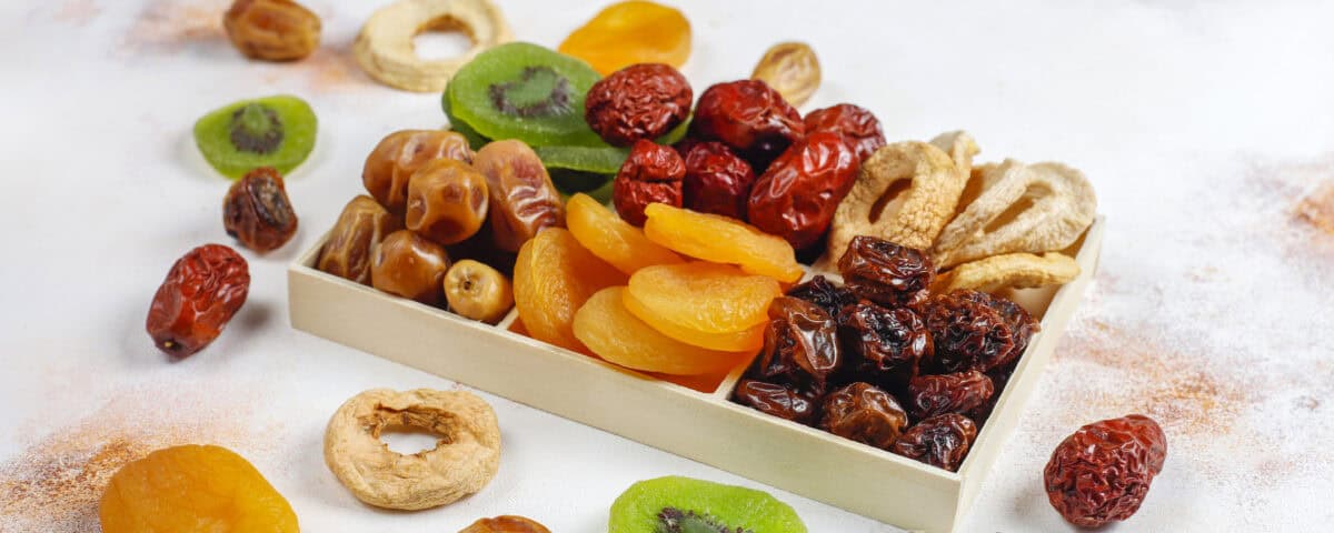 A box of assorted dried fruit snacks—apricots, kiwi, dates, and apples—scattered for healthy snacking tips. | Emping SG