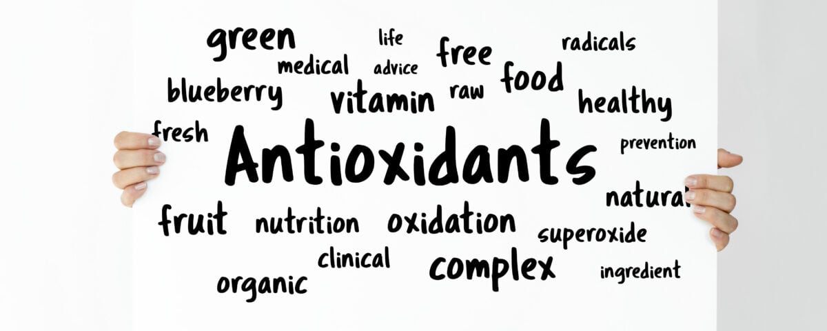 A woman holds a sign with the word "Antioxidants" surrounded by antioxidant-rich superfoods and nutrition terms in black text. | Emping SG