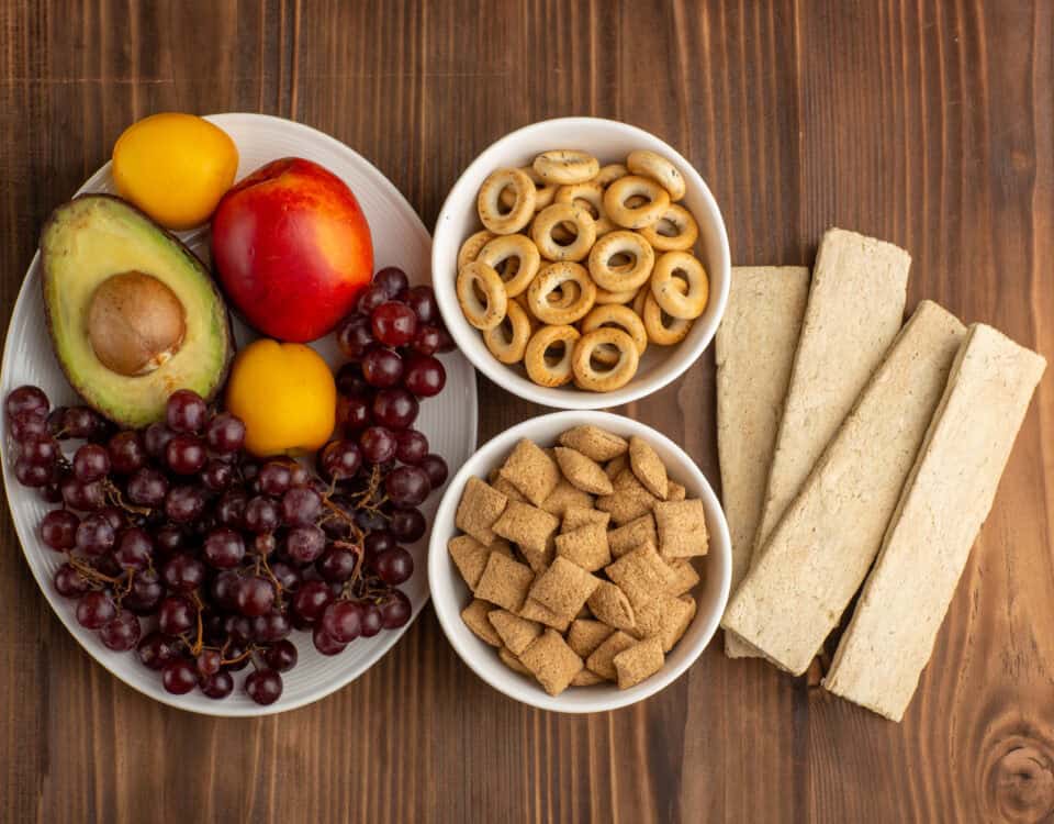 A guide to healthy, satisfying options: grapes, avocado, nectarines, cereal bowls, and breadsticks on a wooden table. | Emping SG