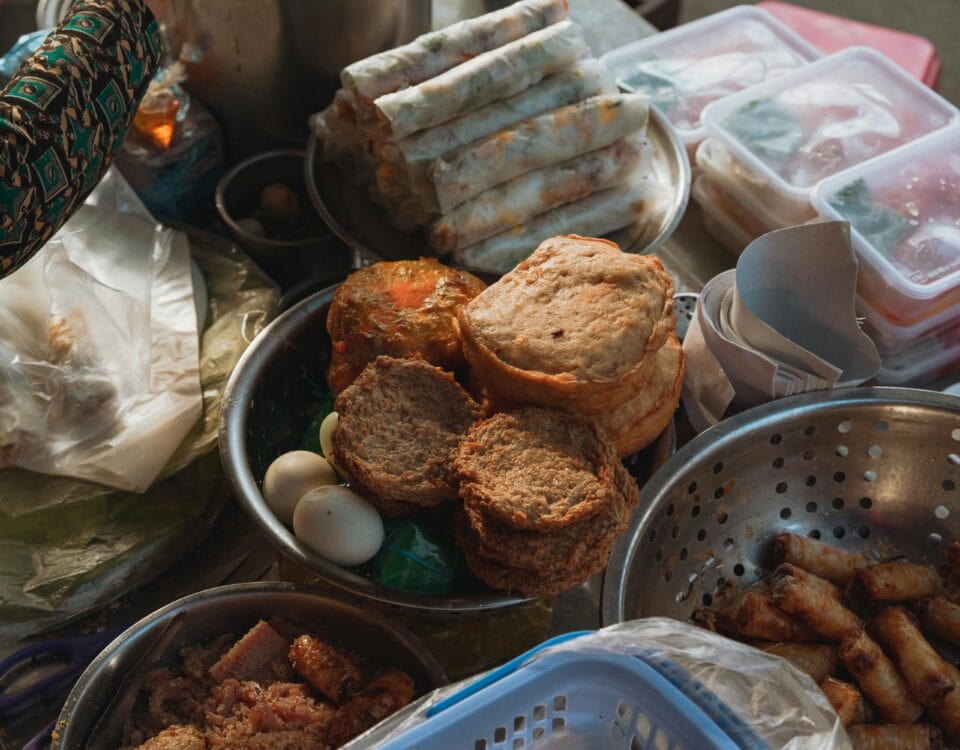 A culinary journey of Vietnamese snacks: spring rolls, fried treats, and eggs displayed in metal bowls and containers. | Emping SG