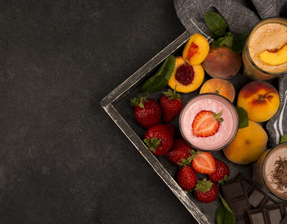 Three glasses of smoothies—strawberry, peach, and chocolate—make a smart nutrition midnight snack on a dark background. | Emping SG