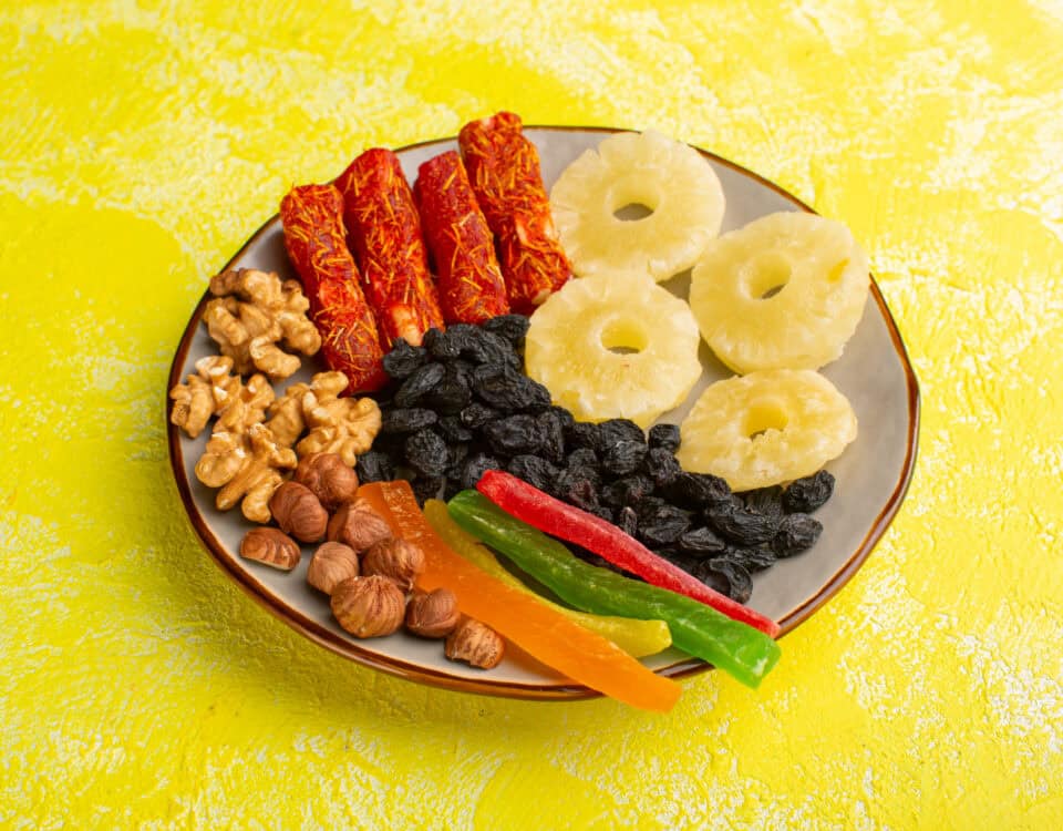 A plate with Premium Fruit Snacks: dried pineapple rings, nuts, berries, and fruit rolls on a yellow background. | Emping SG