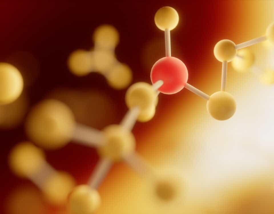 A close-up illustration of purine compounds with yellow and red spheres connected by rods on a warm, blurred background. | Emping SG