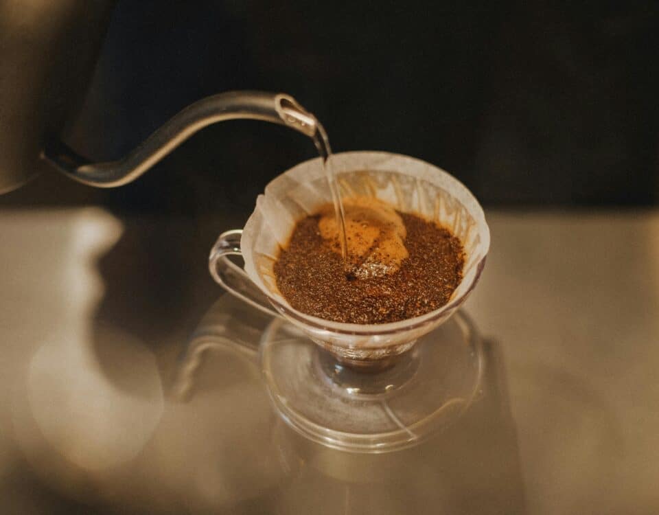 Hot water poured over ground coffee in a glass pour-over dripper for fresh flavour—your guide to Vietnam Drip Coffee. | Emping SG