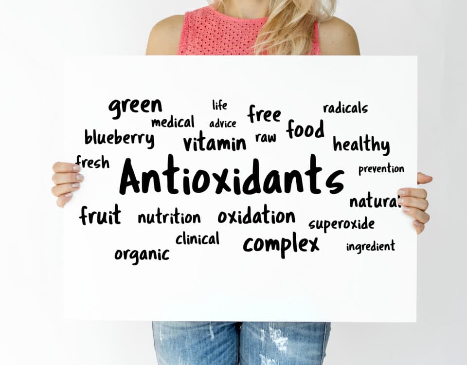 A woman holds a sign with the word "Antioxidants" surrounded by antioxidant-rich superfoods and nutrition terms in black text. | Emping SG